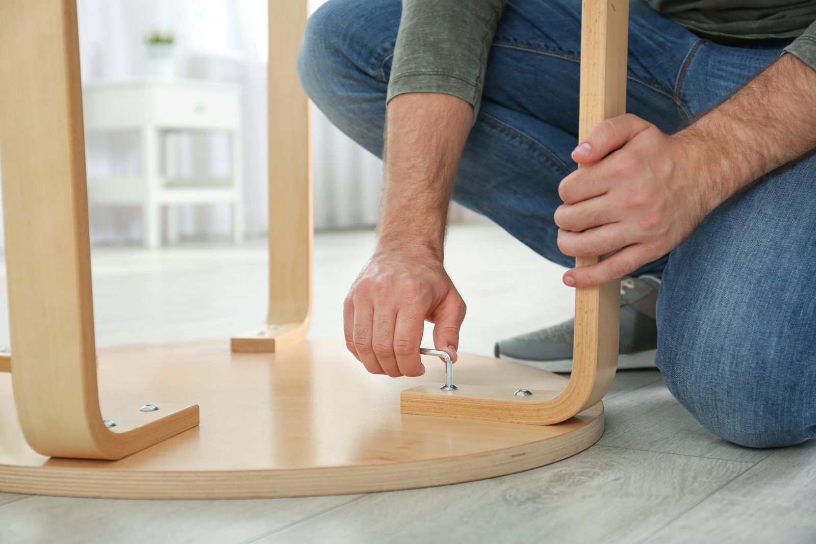 Person stellt Möbelbein eines Schranks auf dem Boden ein